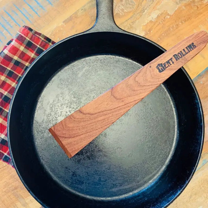 A wooden spatula in the middle of an empty frying pan.