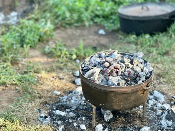Dutch oven with hot coals on a tripod.