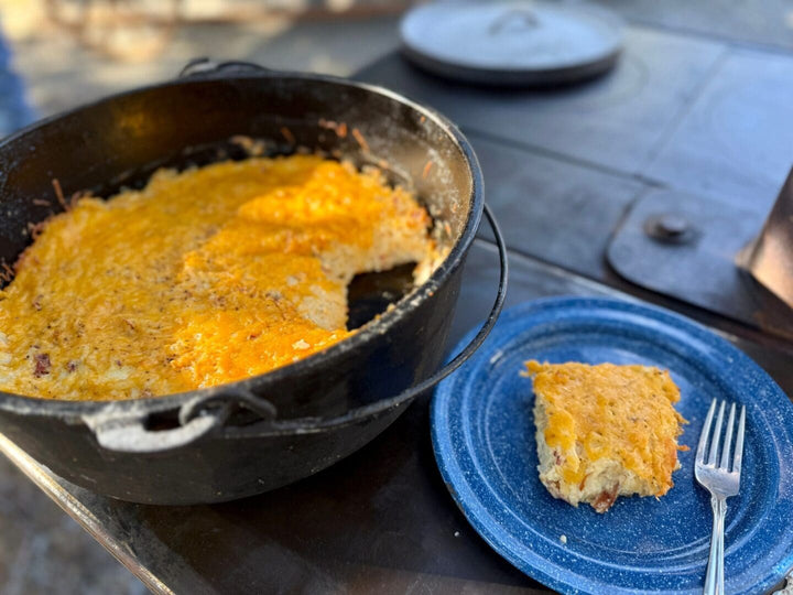 A Dutch oven featuring a delicious hash brown casserole with a piece of casserole on a blue plate